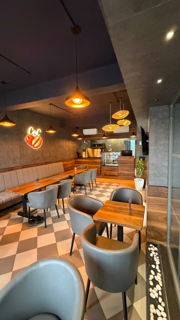 Tables and blue chairs looking toward the entrance at Coffee@Cafe Ambur
