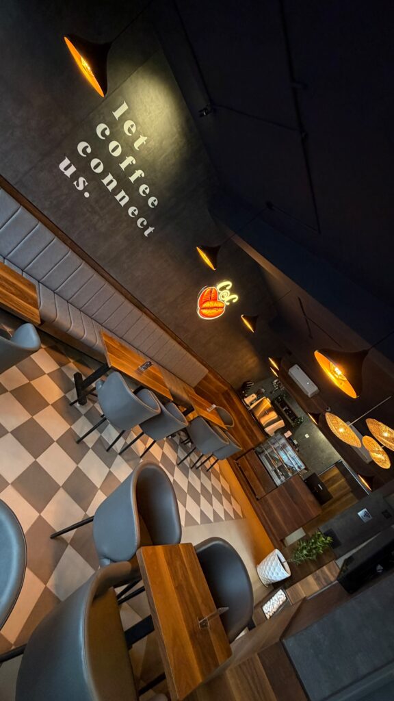 Tilted view of the seating area and neon logo at Coffee@Cafe Ambur
