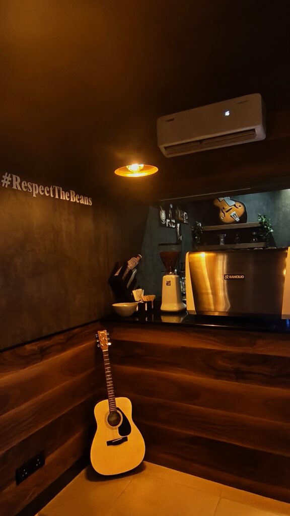 Wall lettering reading #RespectTheBeans with a guitar beside the counter