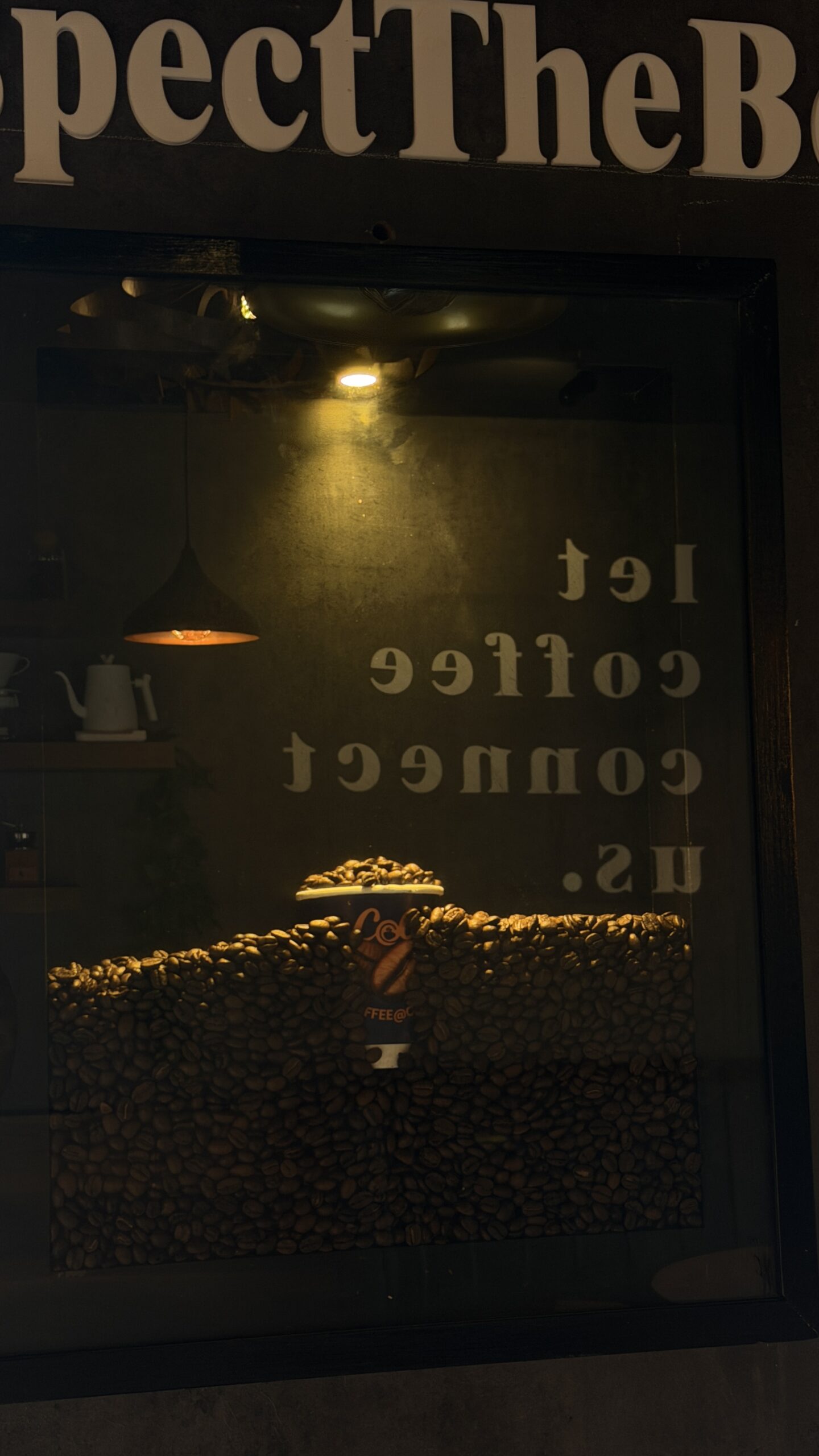 Display window filled with coffee beans under lettering reading respect the beans